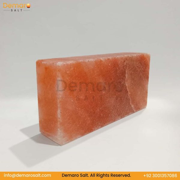 A rectangular block of pink Himalayan salt, resting on a white surface with a gray background. The logo "Demaro Salt" is visible in the top left and watermarked in the center. Contact information is at the bottom of the image.