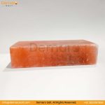 A rectangular block of pink Himalayan salt, resting on a white surface with a gray background. The logo "Demaro Salt" is visible in the top left and watermarked in the center. Contact information is at the bottom of the image.